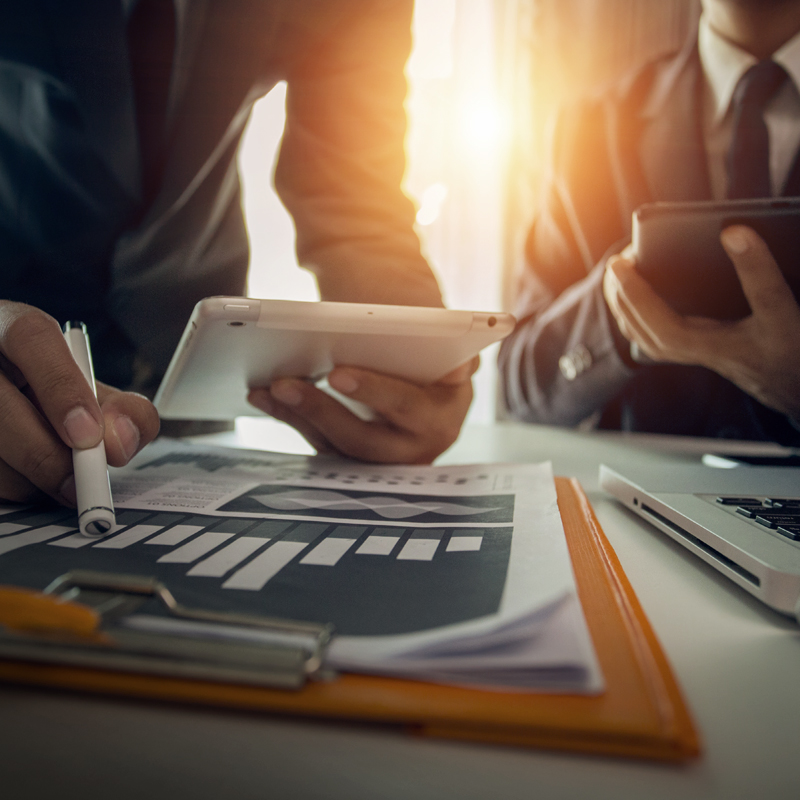 Close-up of portfolio managers reviewing investment research on a table.